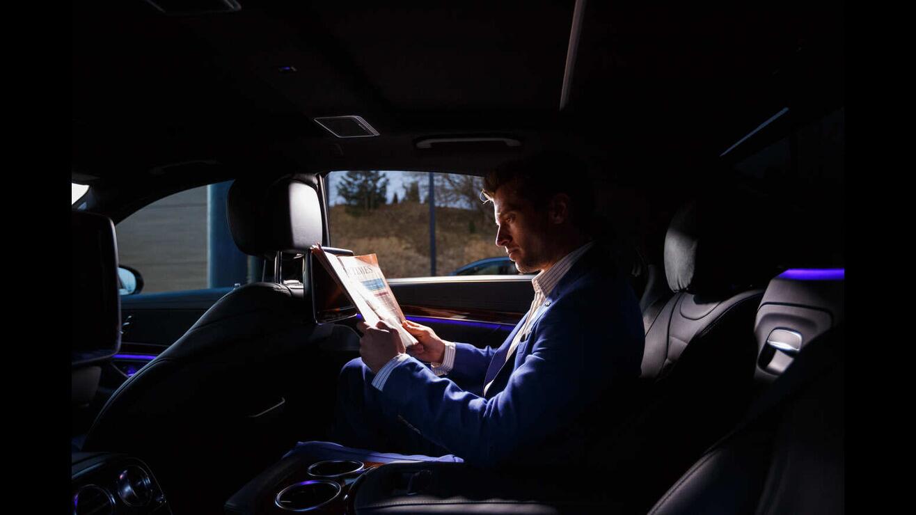 Man reading newspapers in limousine